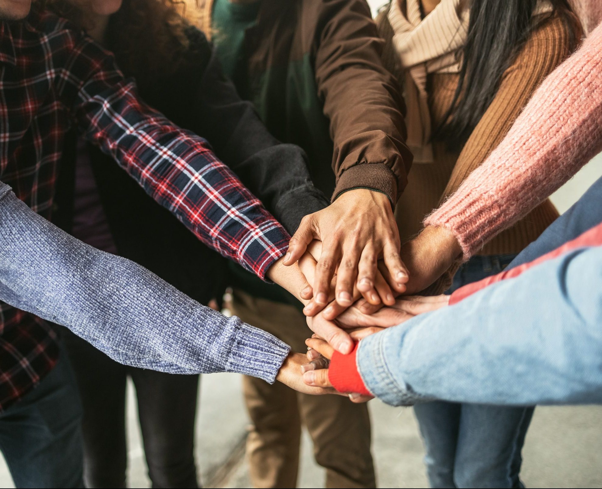 Happy young friends having fun stacking hands together outdoor - Youth people millennial generation concept